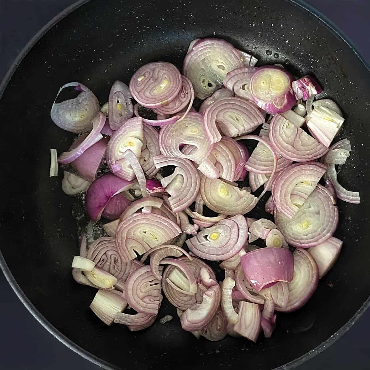 Sliced shallots and onions in a frying pan.