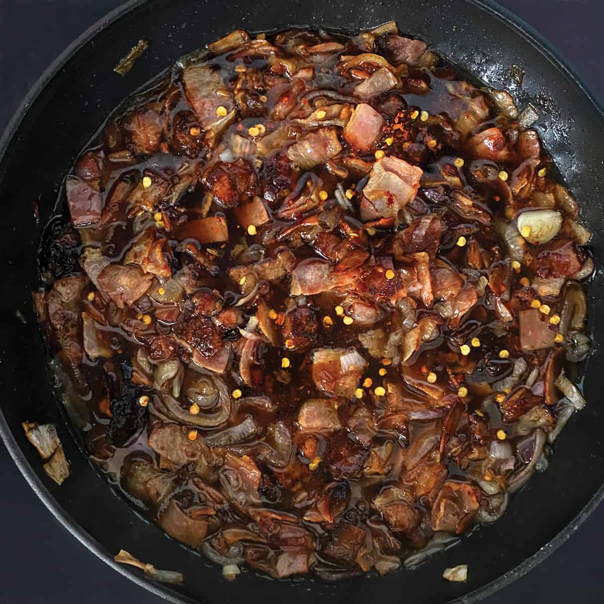 Bacon and shallots with coffee and sugar in a pan.