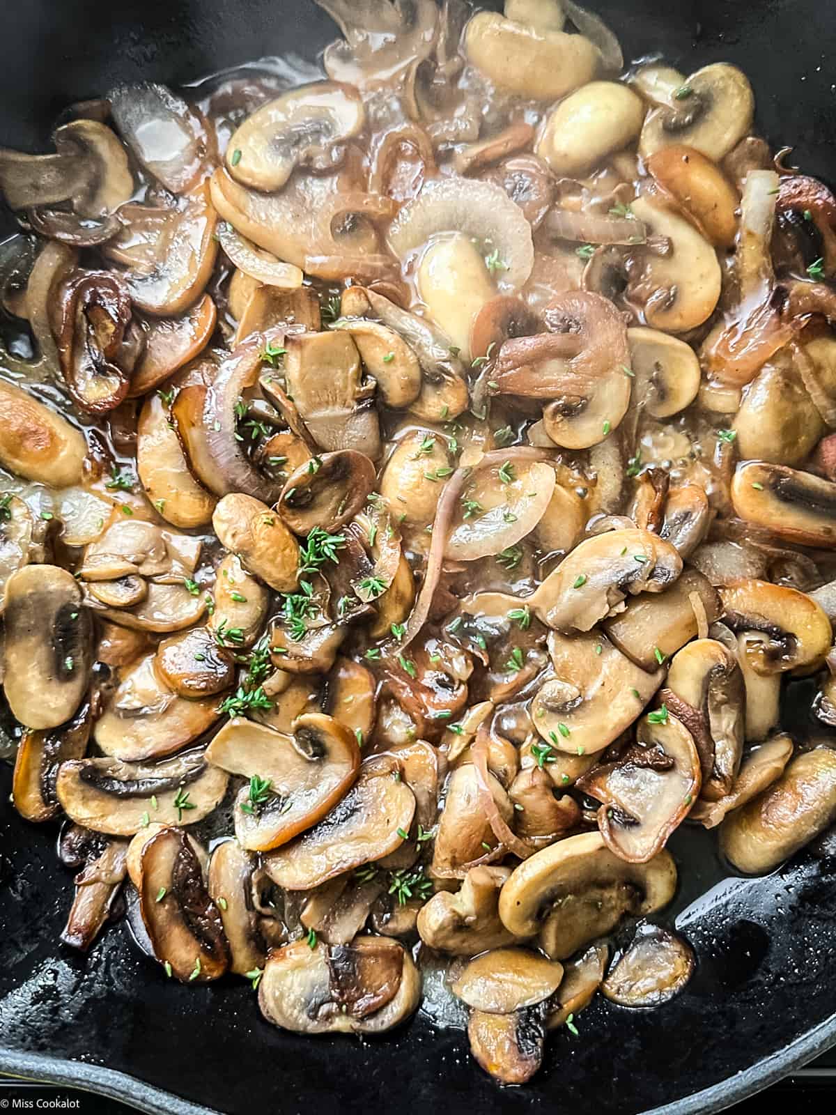 A skillet with mushrooms, and fresh thyme.