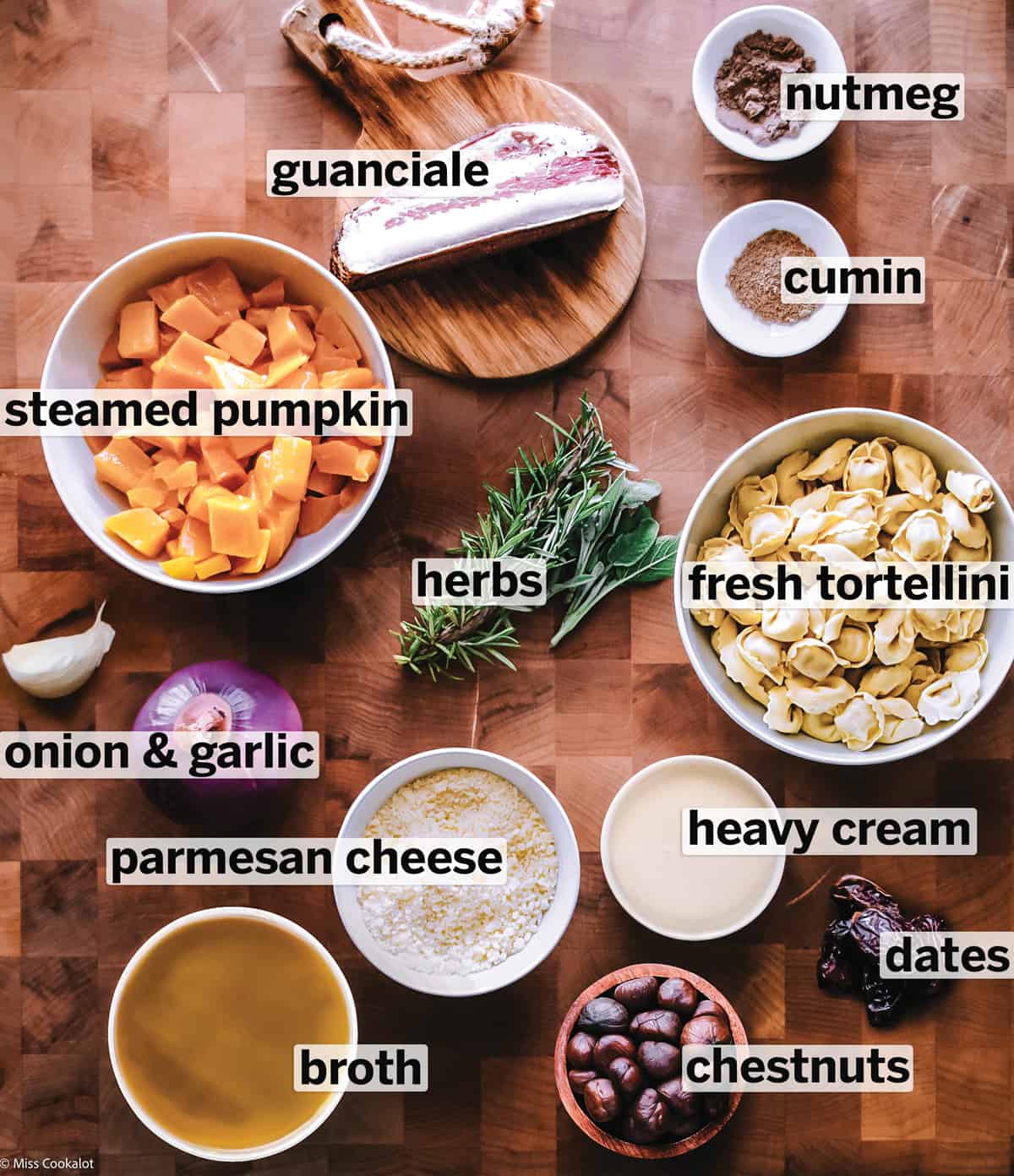 All the ingredients for making pumpkin stew on a butcher block.