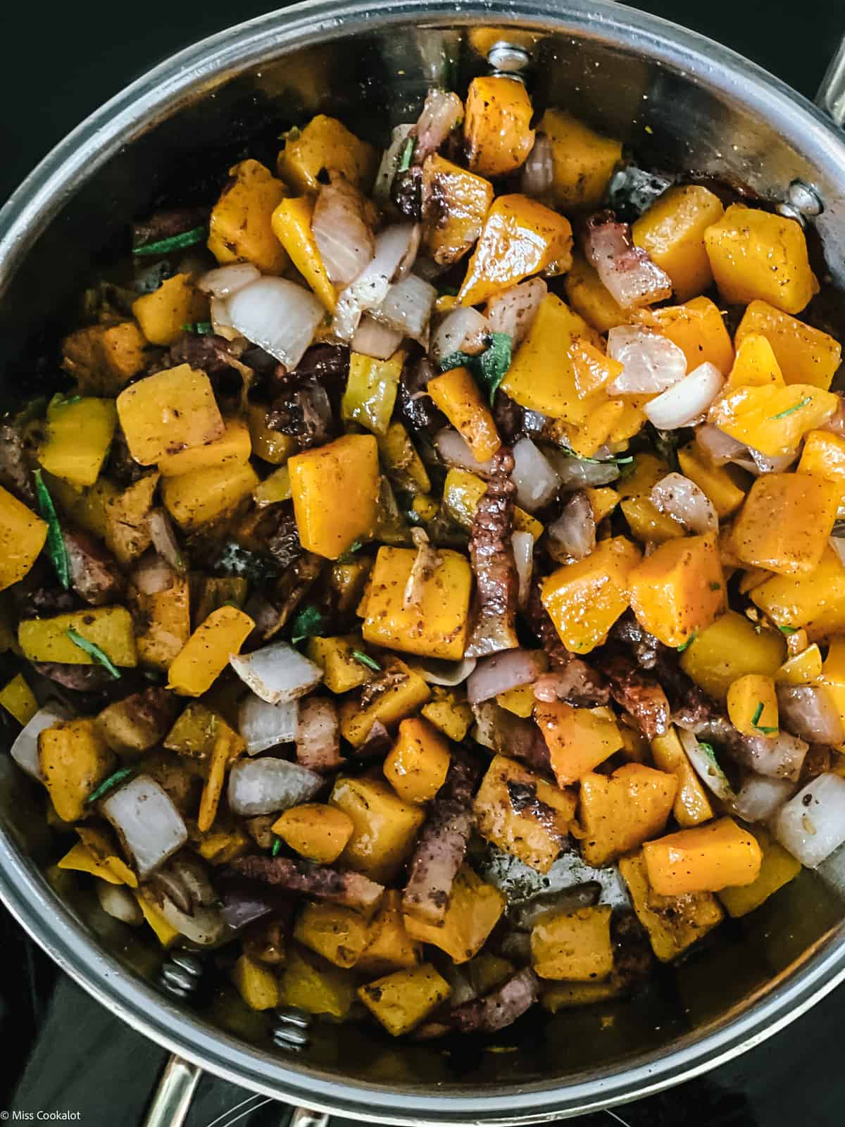 Pumpkin cubes and guanciale pieces chopped onion and garlic in a deep sauce pan.