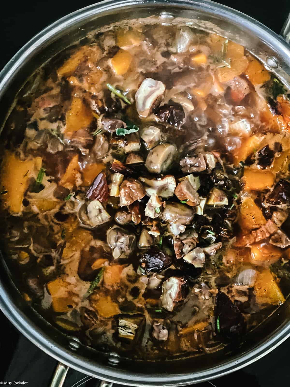 Pumpkin stew with chopped chestnuts and dates on top in a deep sauce pan.