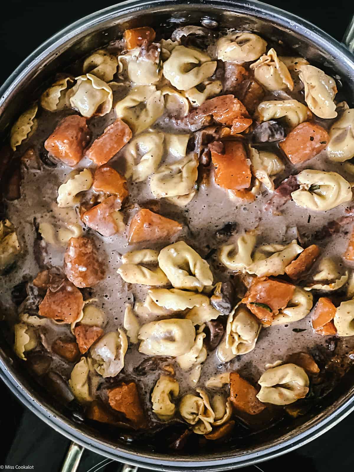 Pumpkin stew with tortellini in a deep sauce pan.