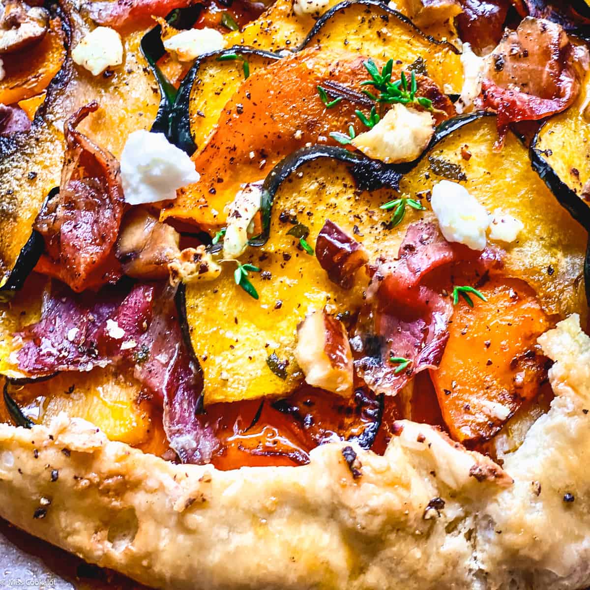 A butternut squash galette with prosciutto and maple syrup on parchment paper.