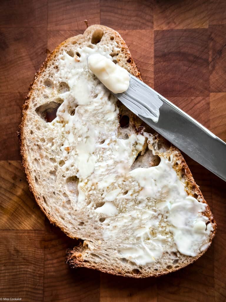 A slice of bread with mayo and a knife  on a table. Over head view.